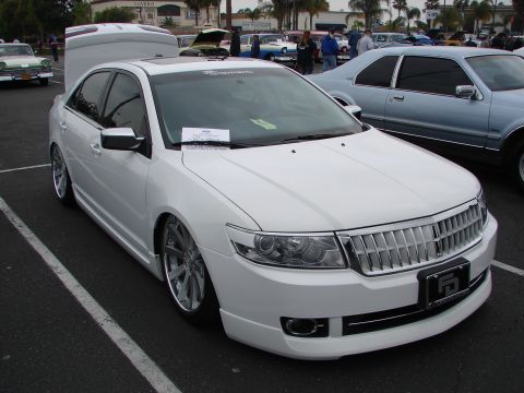 1992 Ford Taurus - White sedan with custom wheels and aftermarket body kit parked at an outdoor event.