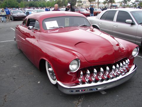 1992 Ford Taurus - A heavily modified red coupe with a distinctive grille sits in a parking lot.