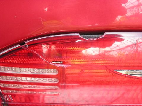 1995 Ford Thunderbird - The rear light assembly of a red vehicle shows significant damage to the lens and housing.