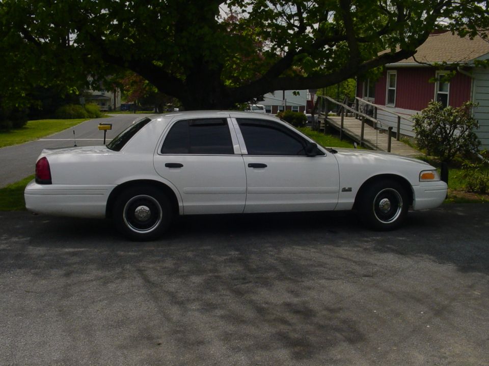 White 2002 Ford Crown Victoria sedan parked on asphalt, side view, tinted windows, chrome trim