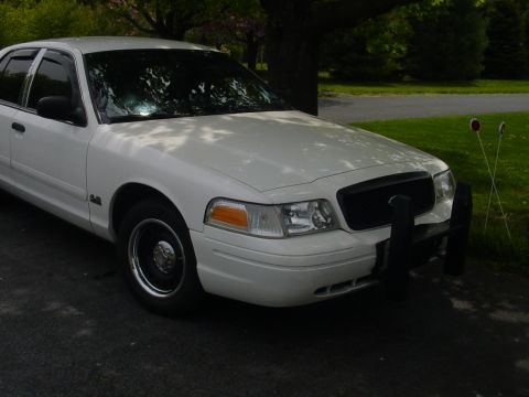 2002 Ford Crown Victoria - A white 2002 Ford Crown Victoria is parked outside, a black push bar on the front.