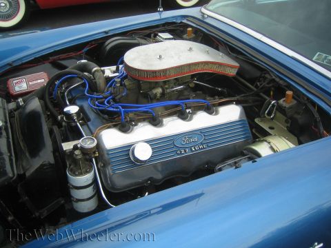 1990 Ford Bronco - chrome-finned Ford 427 SOHC engine with blue plug wires and a finned air cleaner sits in a blue engine bay.