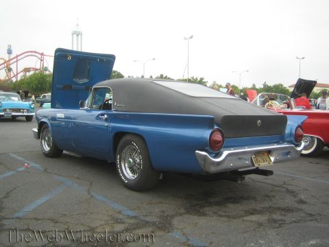 1990 Ford Bronco - Rear three-quarter view of a blue 1950s Ford Thunderbird convertible with black soft top and round taillights at a show.