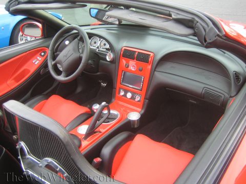 1990 Ford Bronco - Custom convertible interior with red leather seats, black dash, automatic shifter and a pony emblem on the steering wheel.