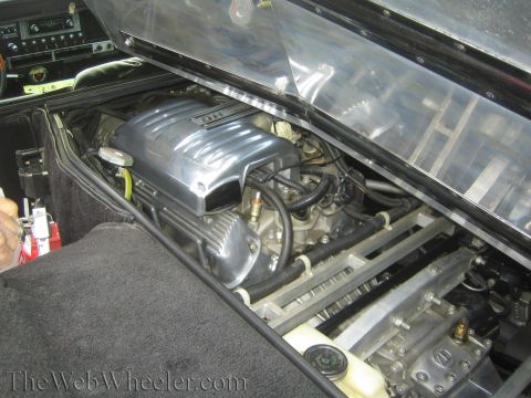 1990 Ford Bronco - polished V8 engine visible under the raised rear deck of a mid-engine sports car.