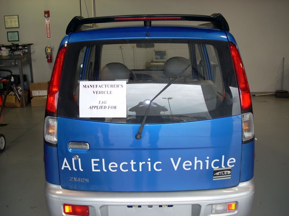 Blue electric vehicle with "All Electric Vehicle" text on the rear, "ZX40S" model designation, and a "MANUFACTURER'S VEHICLE TAG APPLIED FOR" sign