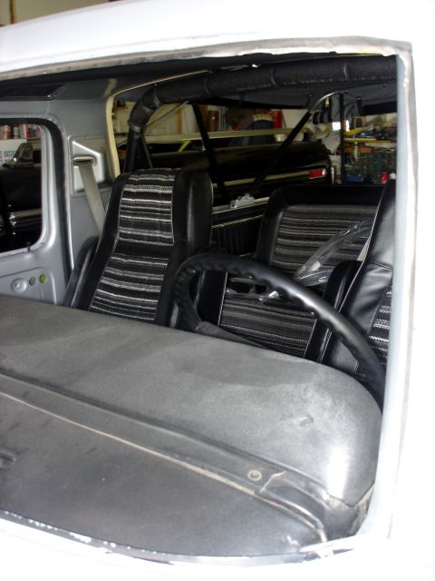 1979 Ford Bronco - The interior of a vehicle shows striped upholstery and a roll bar structure.