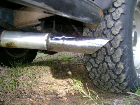 1993 Nissan Pathfinder - The underside of a vehicle shows a shiny exhaust pipe next to a large, off-road tire.