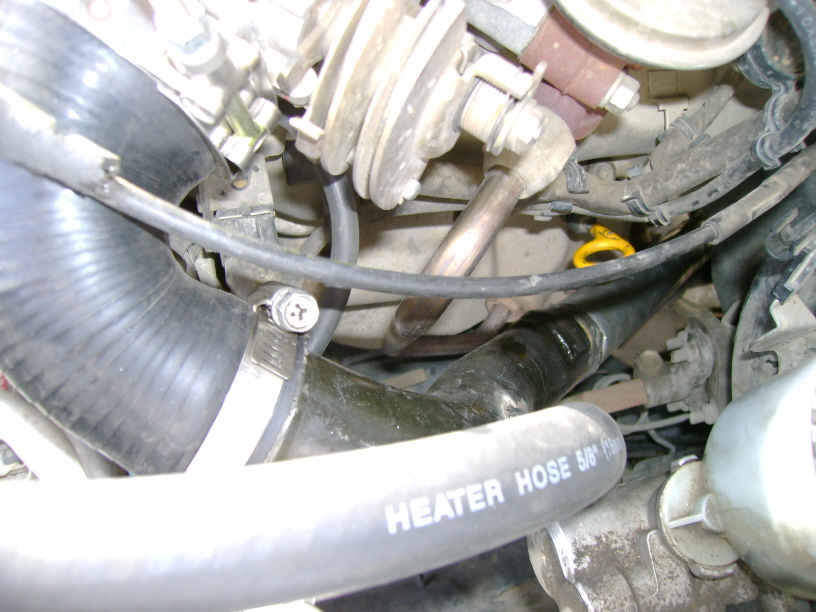 Engine bay close-up of black 5/8 heater hose and clamped radiator hose over engine castings