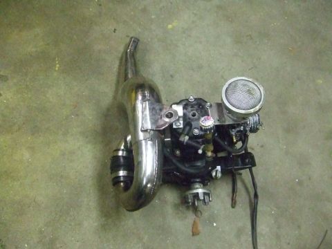 1995 Ford Mustang - A two-stroke engine with a chrome exhaust pipe is displayed on a concrete surface.