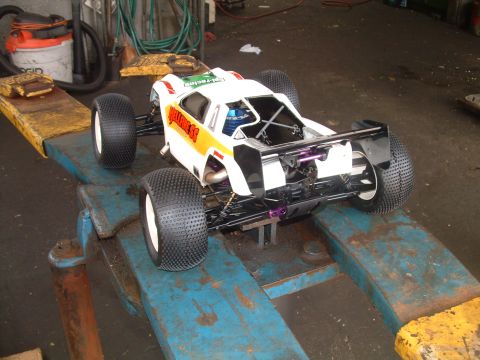1994 Ford Bronco - RC off-road buggy with large tires sits on a mechanic's lift in a garage.
