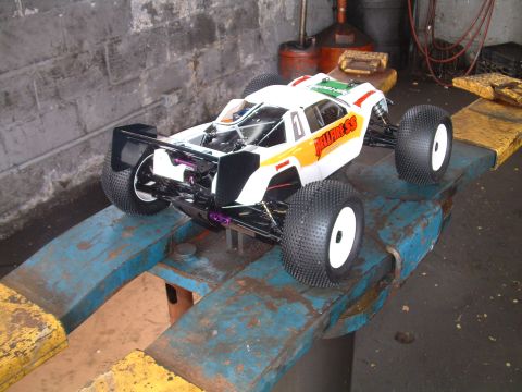 1994 Ford Bronco - A remote control buggy with white, orange, and green graphics sits on a blue metal stand in a workshop.
