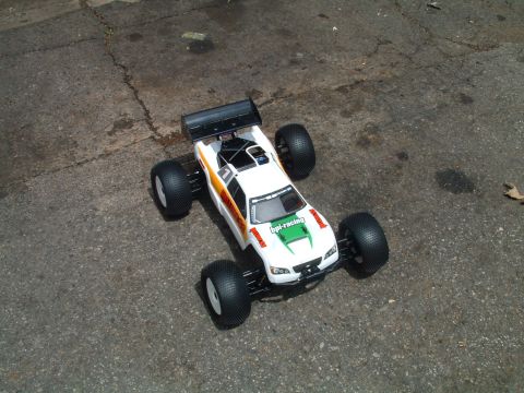 1994 Ford Bronco - A white remote control buggy with racing decals sits on a cracked asphalt surface.