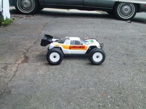 1994 Ford Bronco - A remote control monster truck with "Hellfire SS" graphics sits on pavement, with a car in the background.
