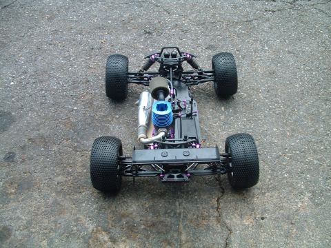 1994 Ford Bronco - A remote control car chassis with a blue engine and large tires is shown from a top-down perspective on an asphalt surface.
