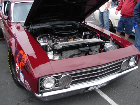 1992 Ford Taurus - A classic red muscle car is displayed with its hood open, revealing the engine and various racing decals on the fender.