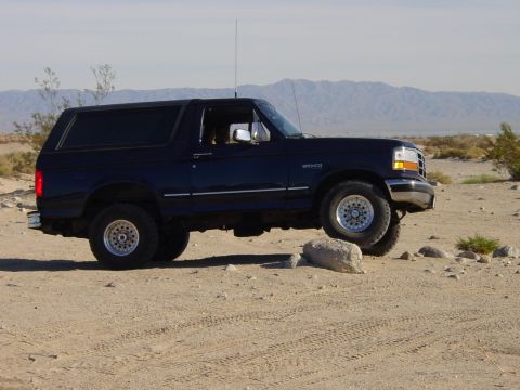 1994 Ford Bronco - 1994 Ford Bronco navigating rocky terrain in a desert environment.