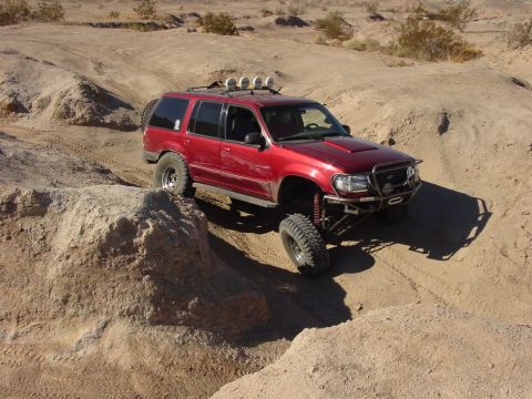 1994 Ford Bronco - A modified red SUV navigates a challenging off-road course in a desert environment.