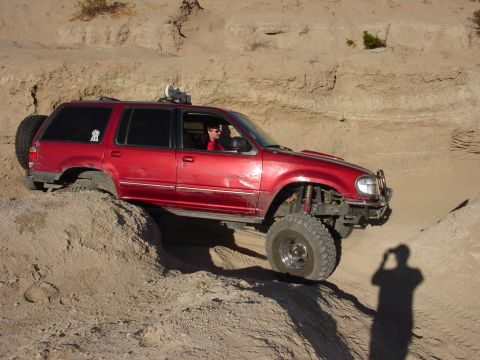 1994 Ford Bronco - Modified red SUV navigating a steep dirt incline off-road.