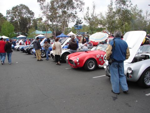 1992 Ford Taurus - A line of classic cars are displayed at an outdoor event, with a red convertible in the foreground.