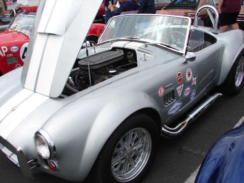 1992 Ford Taurus - A silver AC Cobra replica is displayed with its hood up, revealing the engine and adorned with various racing decals.