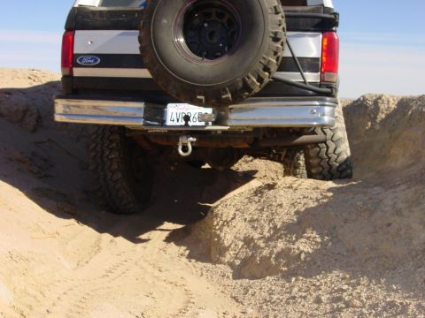 1994 Ford Bronco - Rear view of a 1994 Ford Bronco navigating an off-road trail with a spare tire on the back.