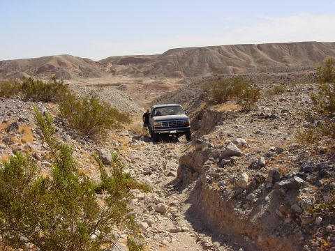 1994 Ford Bronco - A pickup truck navigates a challenging rocky path in a desert landscape, with its grille suggesting a 1994 model year.