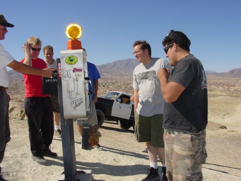 1994 Ford Bronco - People interact near a payphone in a desert setting, with a truck visible behind them.