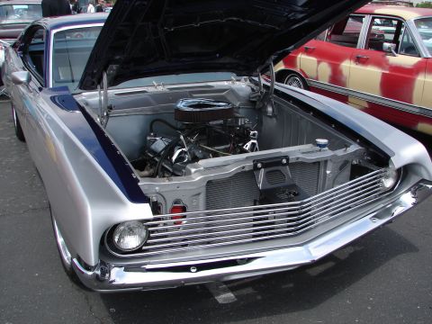 1992 Ford Taurus - Front view of a classic car's engine bay and chrome grille, with another car behind it.