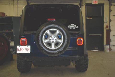 1996 Ford Bronco - The rear of a Jeep Wrangler is shown, a spare tire and a Rocky Road sticker on the back window.