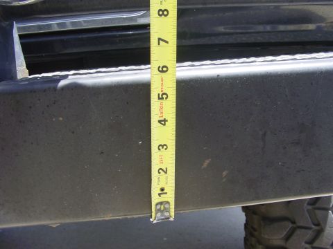 1994 Ford Bronco - A tape measure is used to gauge the height of a vehicle's bumper, indicating approximately 5 inches.