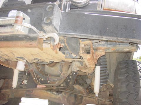 1994 Ford Bronco - Close-up view of the front bumper and suspension system of an off-road vehicle, showing rust and wear.