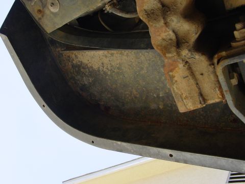 1994 Ford Bronco - Close-up of a vehicle's undercarriage, focusing on a rusty bumper and mounting bracket.