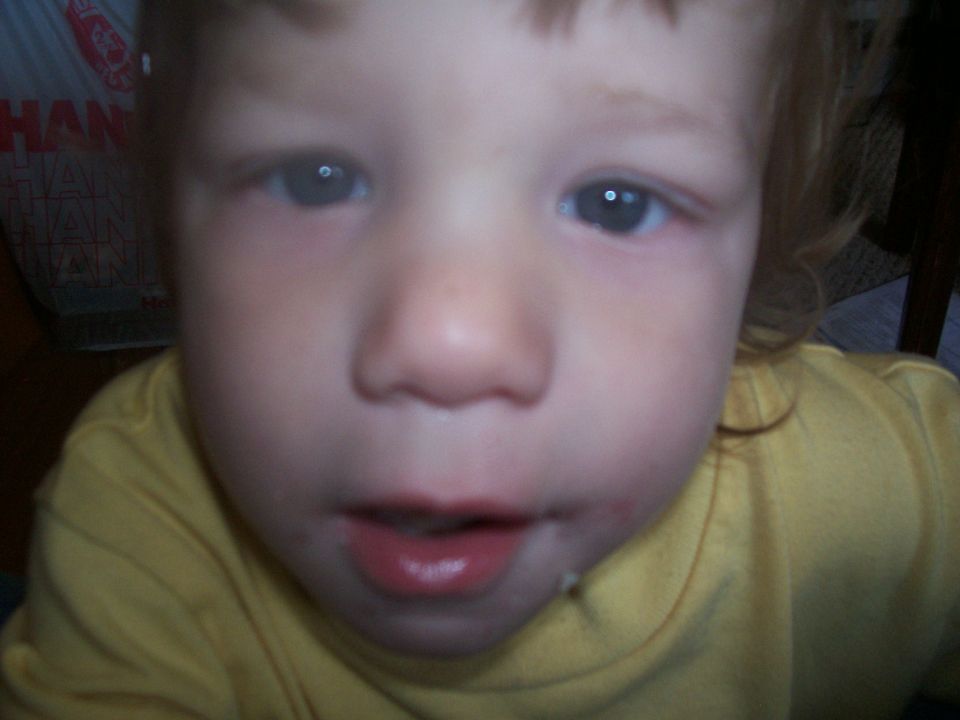 Close-up of a young child's face in a yellow shirt indoors
