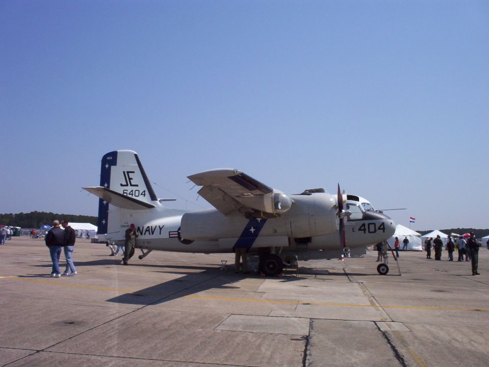 Grumman E-1 Tracer aircraft with 'NAVY' and 'JE 6404' markings on tarmac