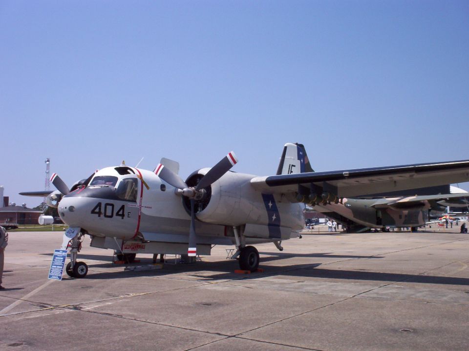 Gray twin-engine turboprop aircraft with red and white striped propellers, marked with '404 E' on the nose