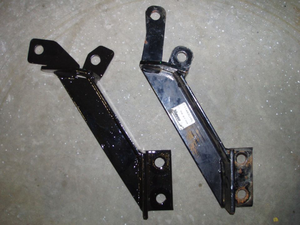 Two black metal brackets with mounting holes. One has a label