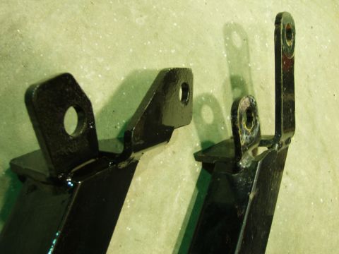 1979 Ford Bronco - Two black metal brackets with mounting holes are shown against a textured background.