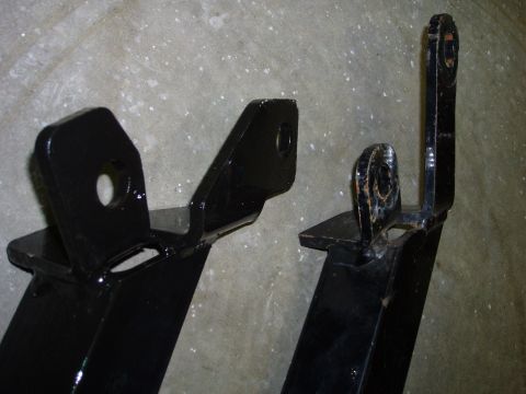 1979 Ford Bronco - Close-up of two black metal brackets, possibly for a vehicle, against a concrete background.
