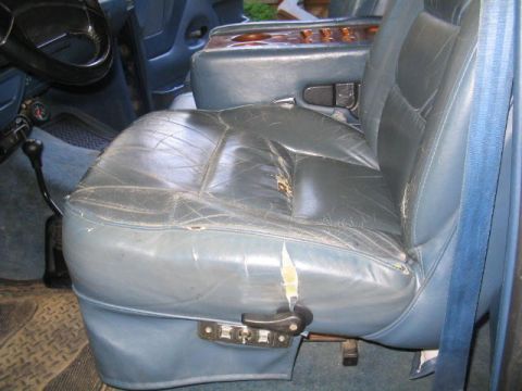 1979 Ford Bronco - Interior view of a worn gray/blue leather bench or bucket seat with heavy cracking and a large tear on the front edge of the cushion. A chr…