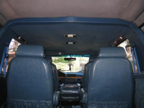 1979 Ford Bronco - Interior of a Ford Bronco viewed from the rear cargo area looking forward, showing two blue leather bucket seats, a center console, the das…