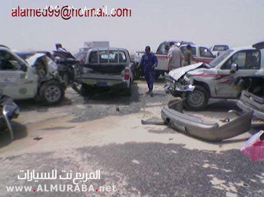 Wrecked white car with red and white racing stripes, front bumper detached