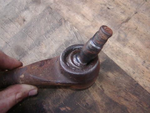 1991 Ford Bronco - Close-up of a rusty tie rod end, a component of a vehicle's steering system.