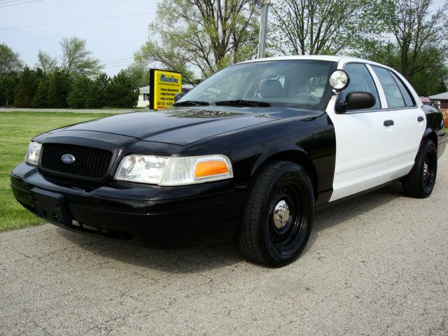 Black and white police car parked on pavement. It's a 2003 Ford Crown Victoria