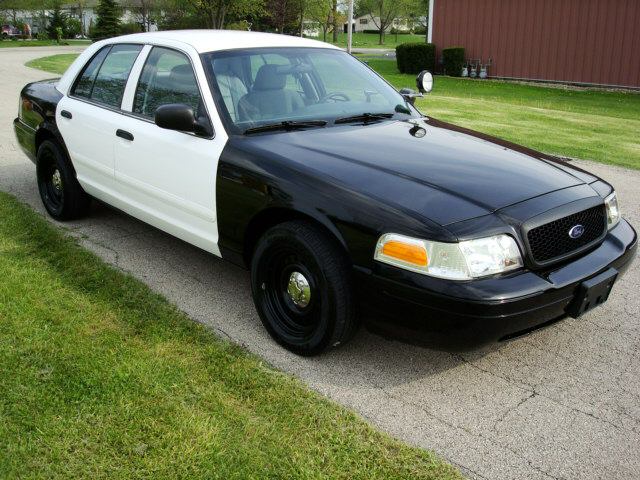 Black and white Ford Crown Victoria police car parked on a driveway