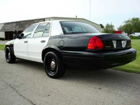 2003 Ford Crown Victoria - Rear three-quarter view of a black and white police sedan with black wheels.