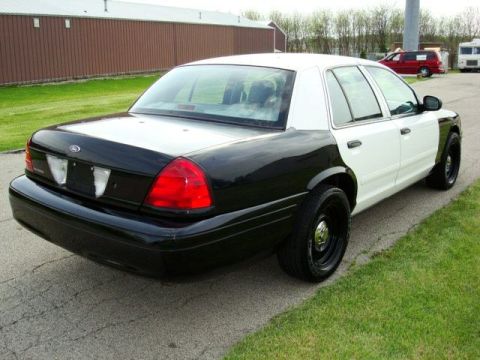 2003 Ford Crown Victoria - This two-tone Ford Crown Victoria is viewed from the rear-left quarter, revealing its distinct black and white paint scheme.