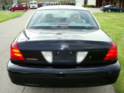 2003 Ford Crown Victoria - This black 2003 Ford Crown Victoria Police Interceptor is seen from the rear, a white roof and police markings.