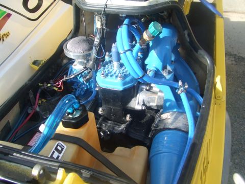 1995 Ford Mustang - The engine compartment of a yellow personal watercraft, prominent blue hoses and engine components.