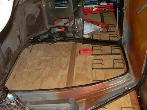 1986 Ford Bronco - The interior of a vehicle shows a wooden floor and seat mounting hardware, suggesting a restoration or modification project.